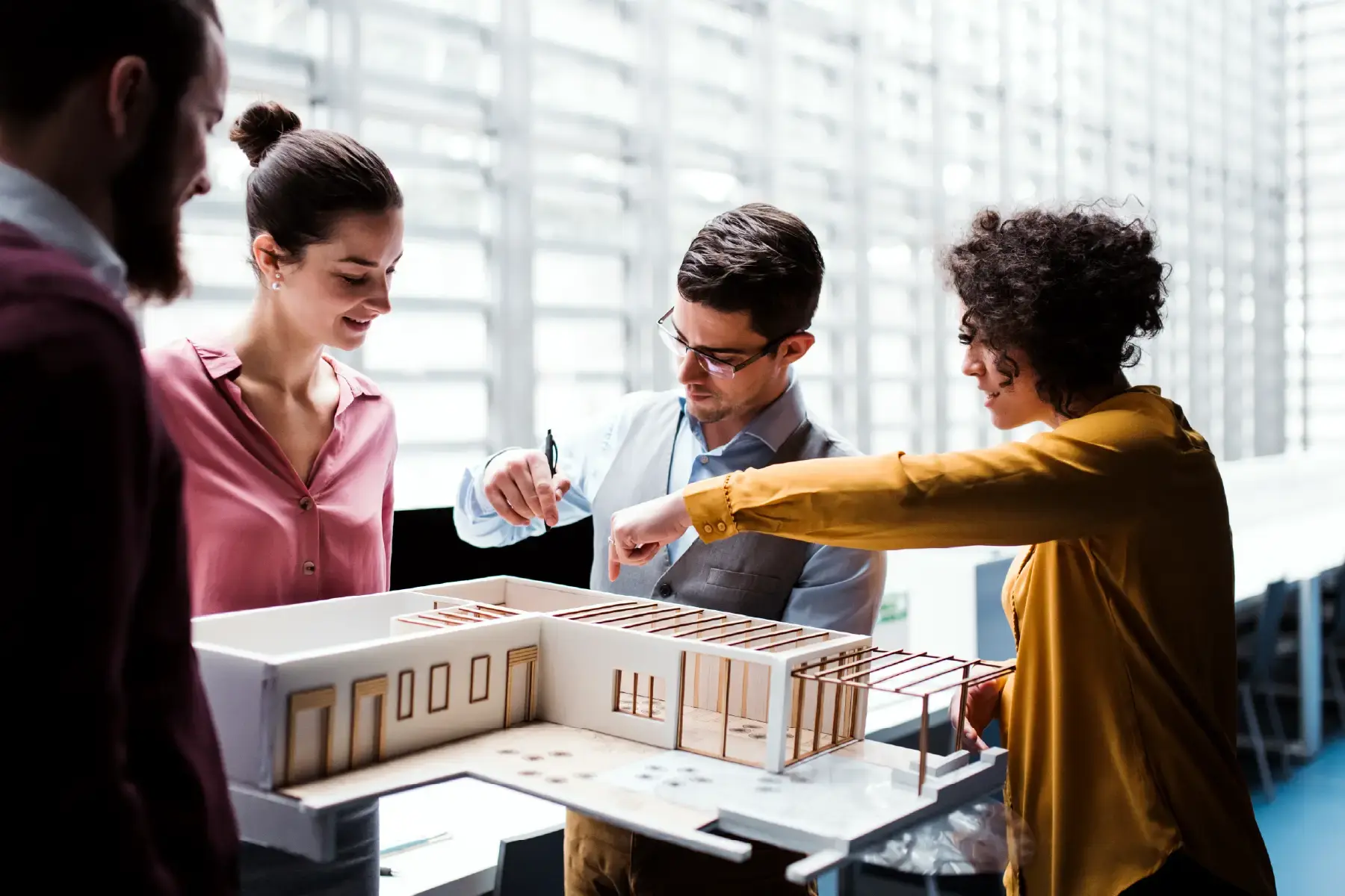 Architects and planners discussing a building model around a table in a design studio