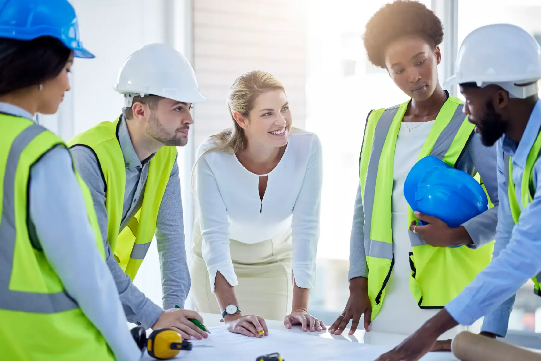 Engineers and construction workers reviewing blueprints on-site, showcasing collaboration and technical planning