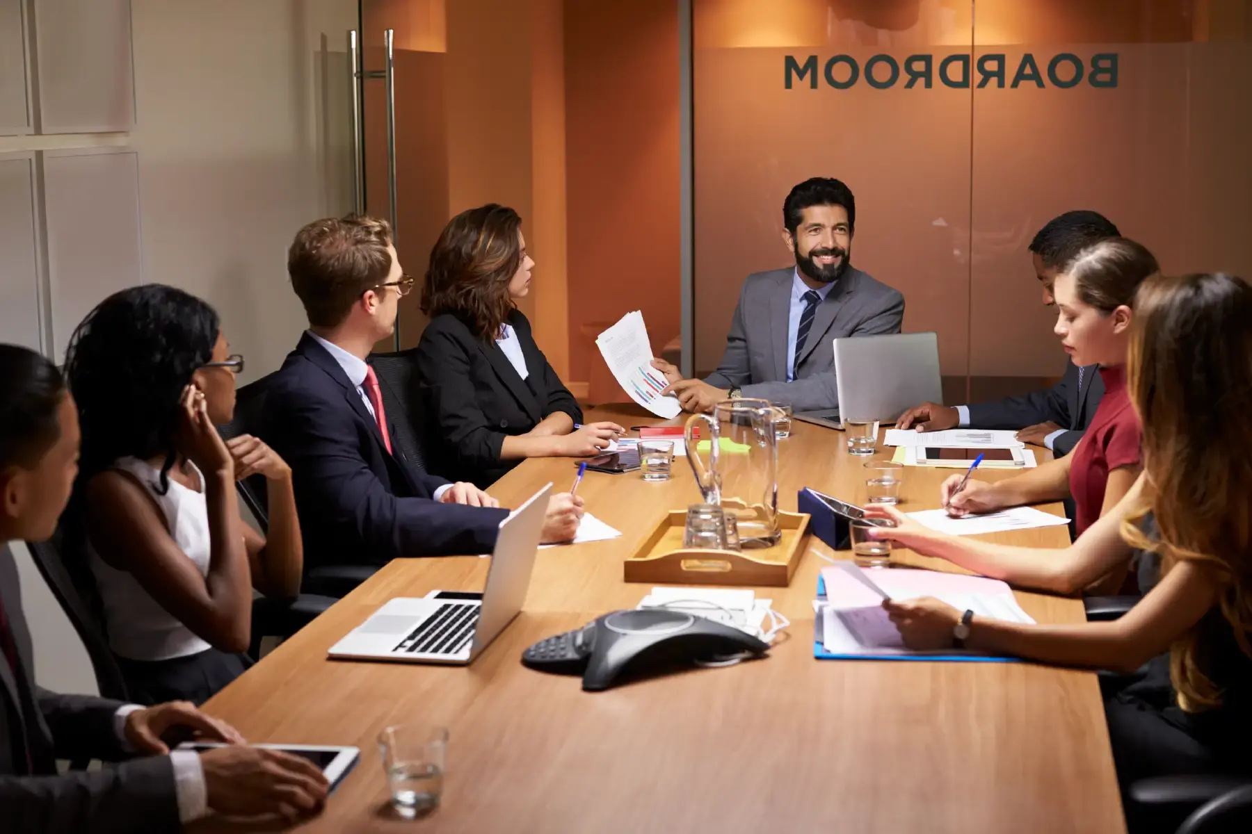Consultants and clients in a formal boardroom discussing strategic advisory plans