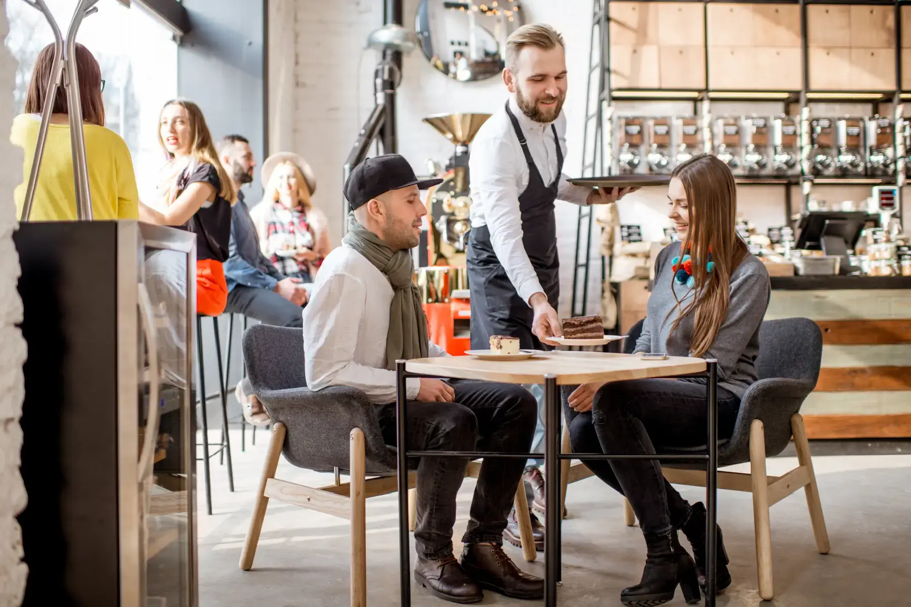 Customers ordering and enjoying drinks in a trendy café, reflecting the hospitality-driven culture of modern food and beverage businesses