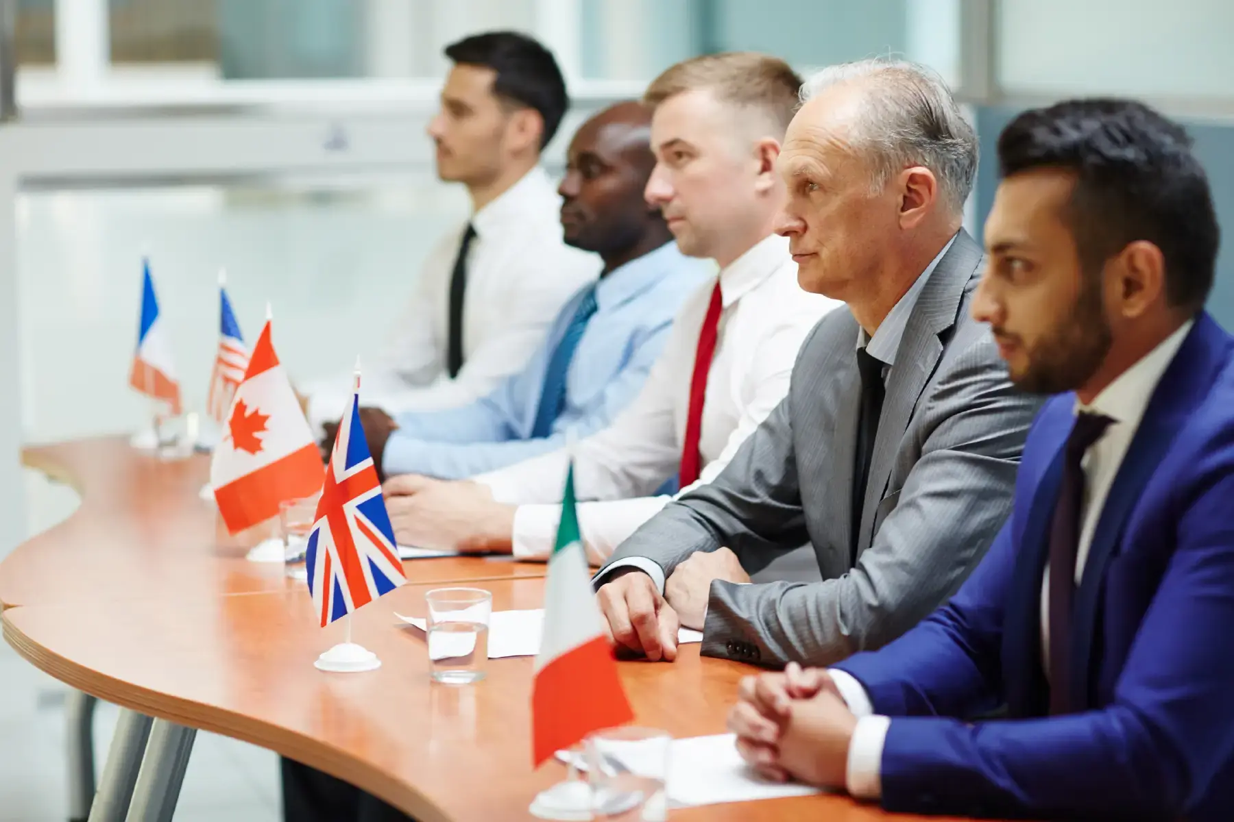 Global representatives seated at a diplomatic table with flags, representing government collaboration and public service strategy