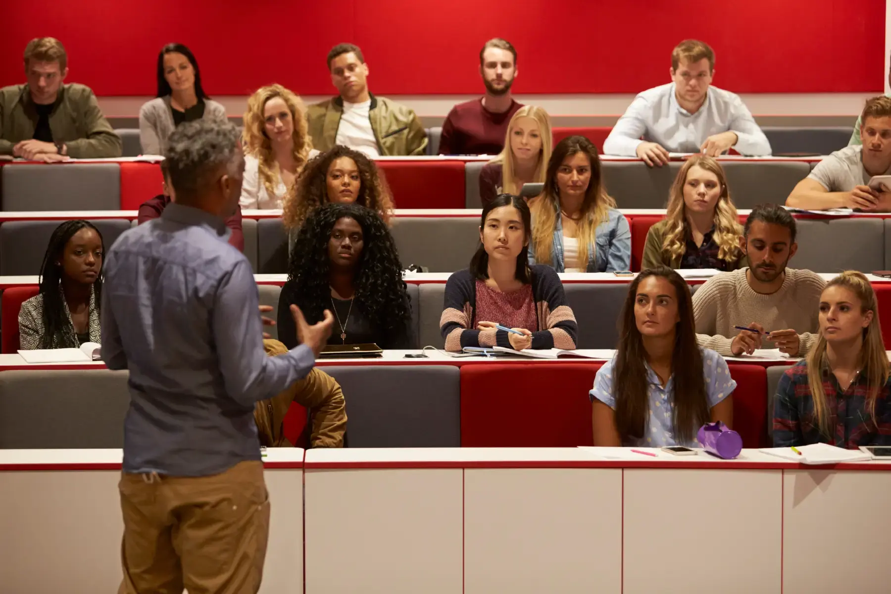 University lecturer addressing a diverse cohort in a modern lecture hall, symbolising thought leadership in higher education