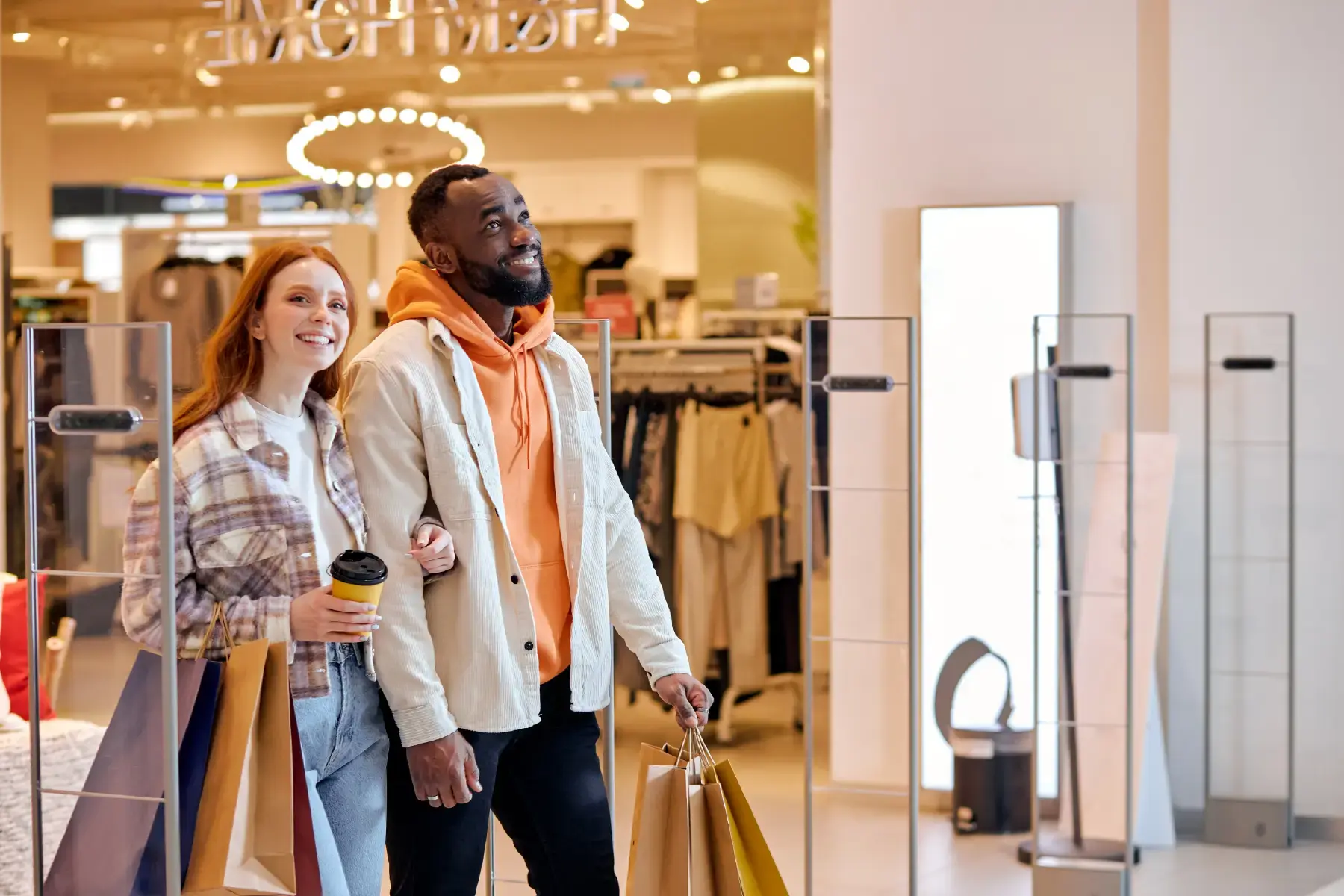 Smiling couple with shopping bags walking out of a modern fashion store, capturing the essence of high-street retail and consumer lifestyle